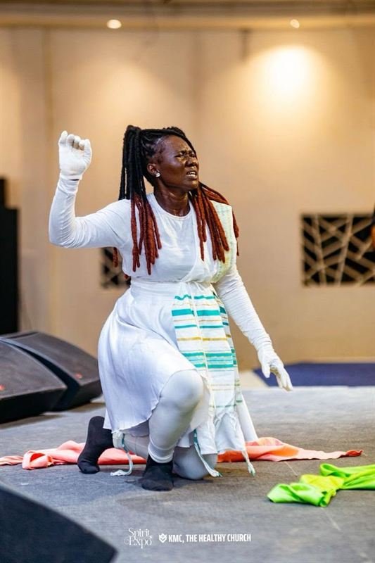 A dance minister kneeling in worship on stage